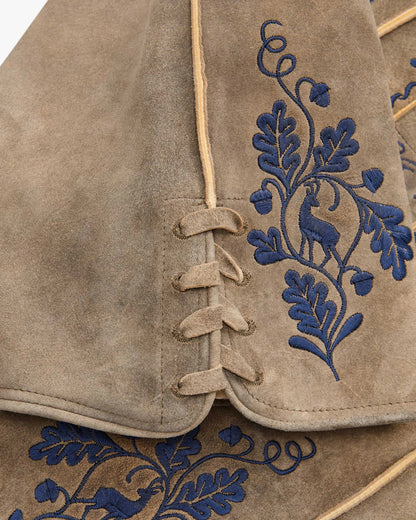 Close-up of a brown leather vest with blue embroidered designs on a white background