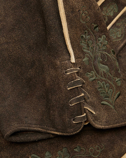 Close-up of a brown fabric with embroidered green leaves on a garment.