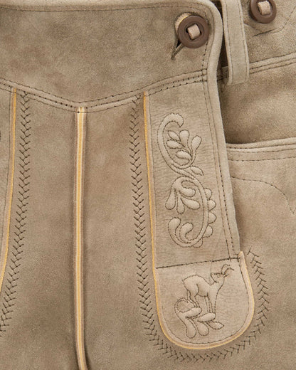 Close-up of brown leather pants with intricate stitching and a embroidered design.
