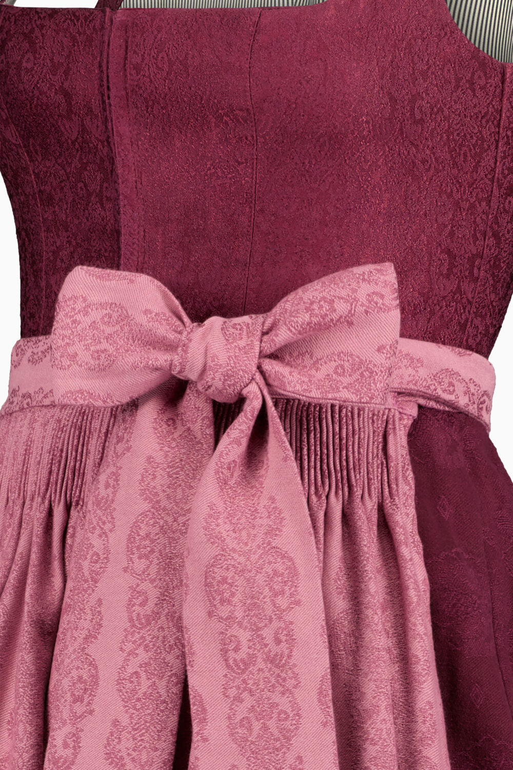 Close-up of a burgundy dress with a pink patterned sash and bow.