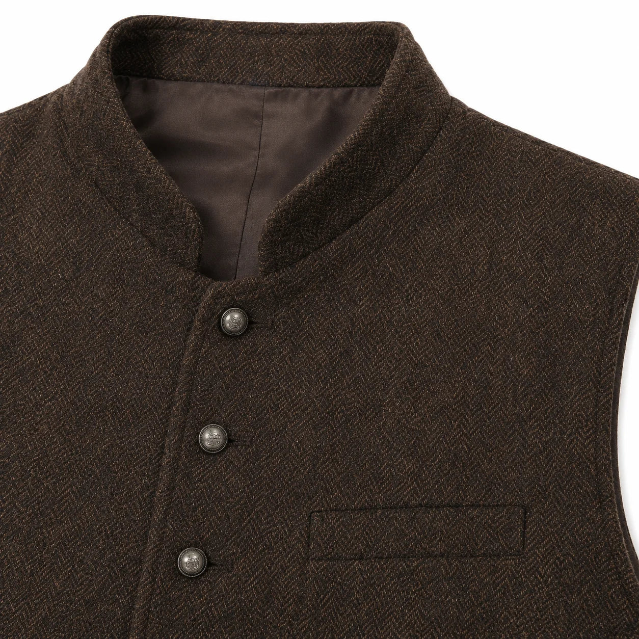 Close-up of a dark brown herringbone tweed vest with a mandarin collar, three dark buttons, and a welt pocket on the chest.