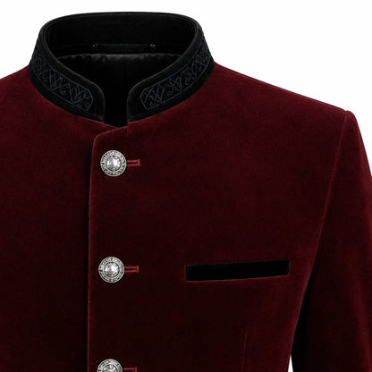 Close-up of a men's traditional-style jacket in deep burgundy velvet with a black mandarin collar featuring embroidered detailing, silver-tone decorative buttons, and a black chest pocket on a white background.