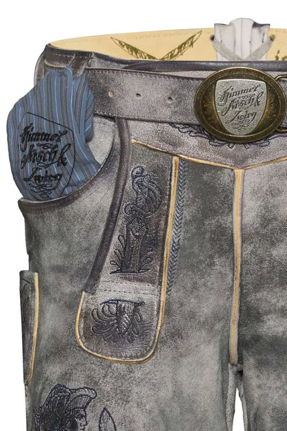 Close-up of traditional leather pants with embroidered details and a brand logo.