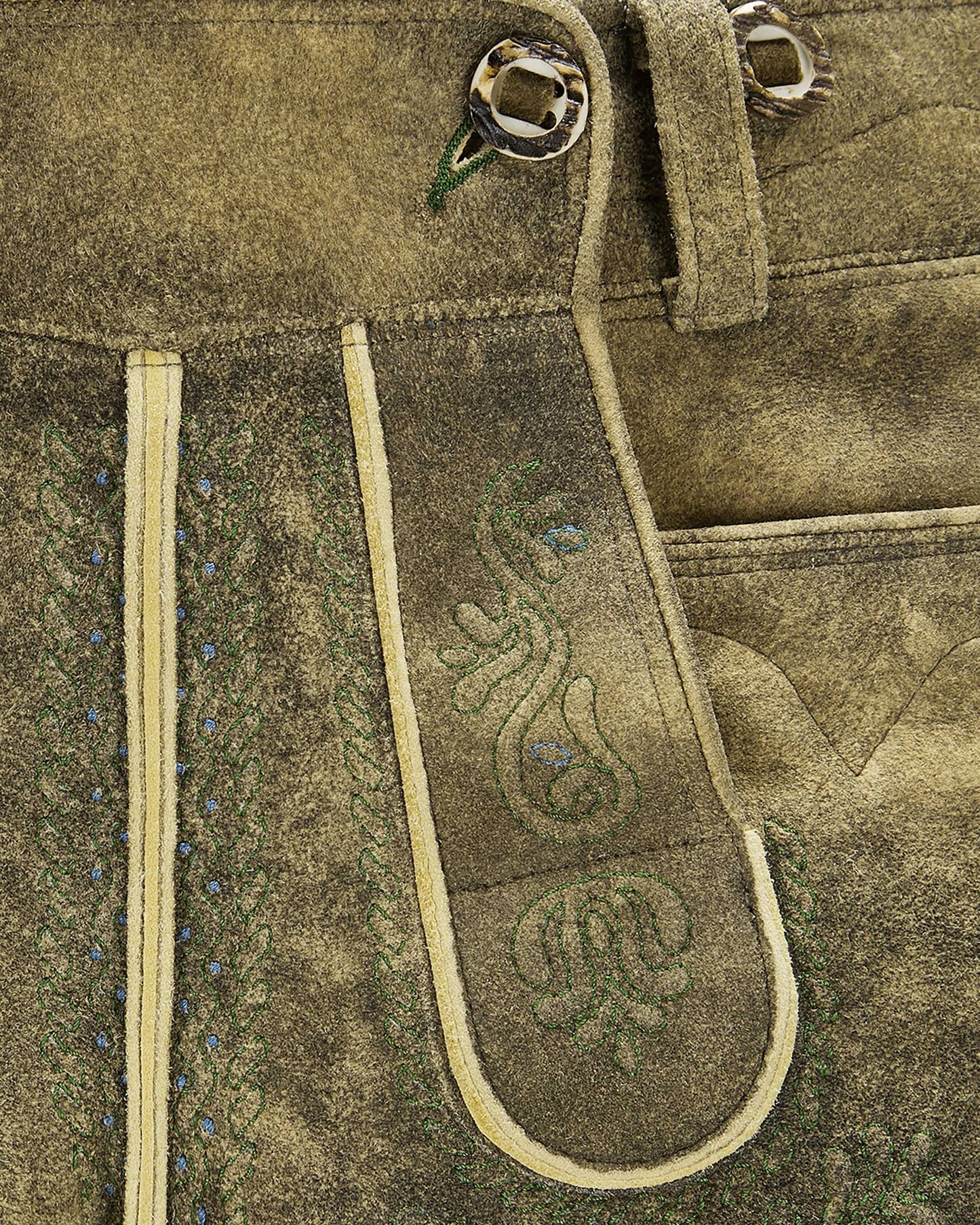 Close-up of a brown leather belt with decorative stitching on a textured fabric background