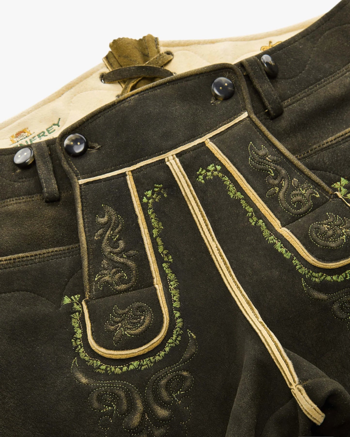 Traditional black leather shorts with gold embroidery on a white background