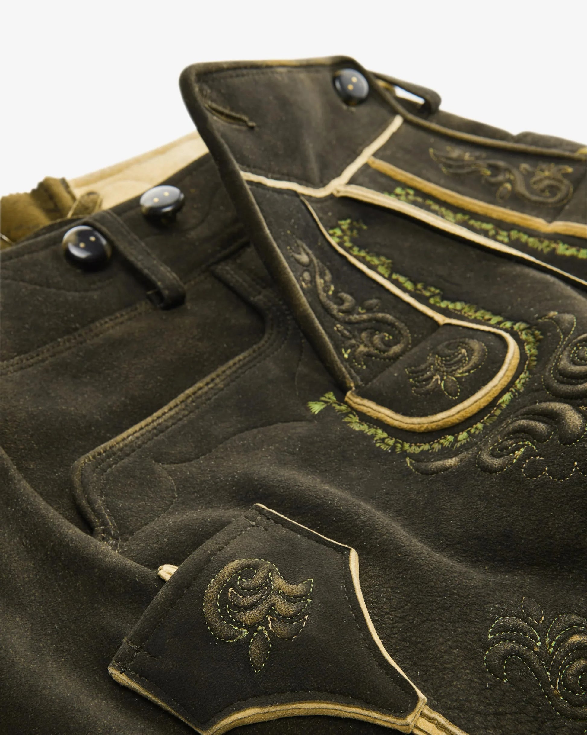 Traditional black leather shorts with gold embroidery on a white background
