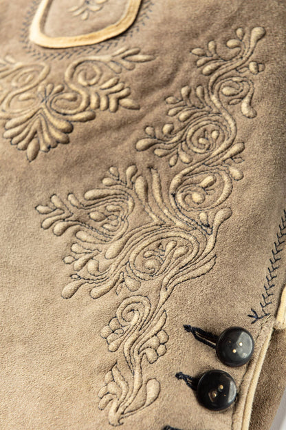 Close-up of a beige fabric with intricate floral embroidery and black buttons.