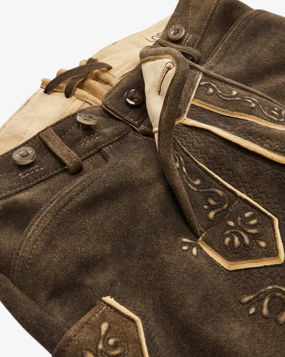 Close-up of a brown leather jacket with decorative stitching on a white background