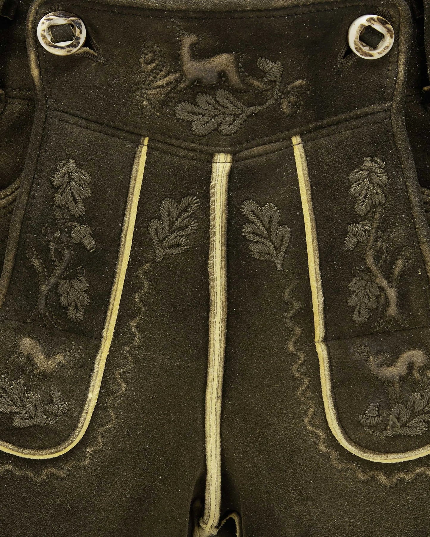 Dark fabric with embroidered patterns and decorative buttons