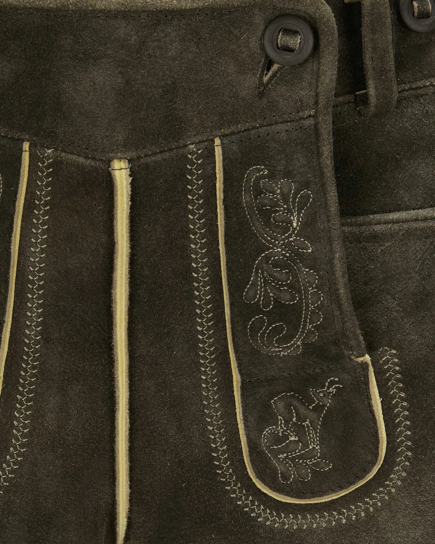 Close-up of brown leather pants with decorative stitching and patterns.