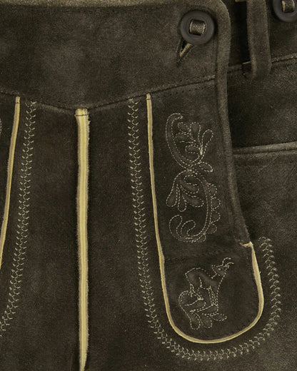 Close-up of brown leather pants with decorative stitching and patterns.