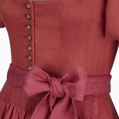 Close-up of a red dress with buttons and a bow on a white background