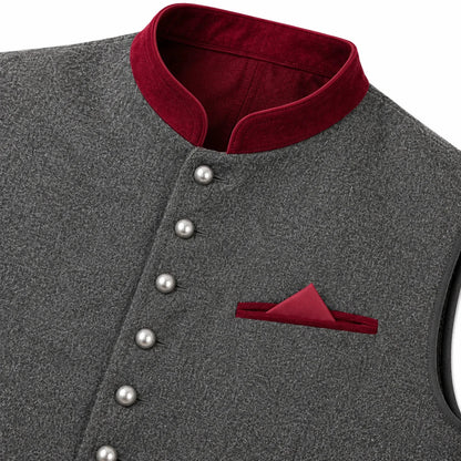 Close-up of a dark gray textured waistcoat with a contrasting deep red velvet stand collar, decorative silver buttons, and a matching red pocket square.