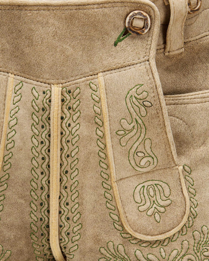 Close-up of a beige leather bag with intricate green embroidery