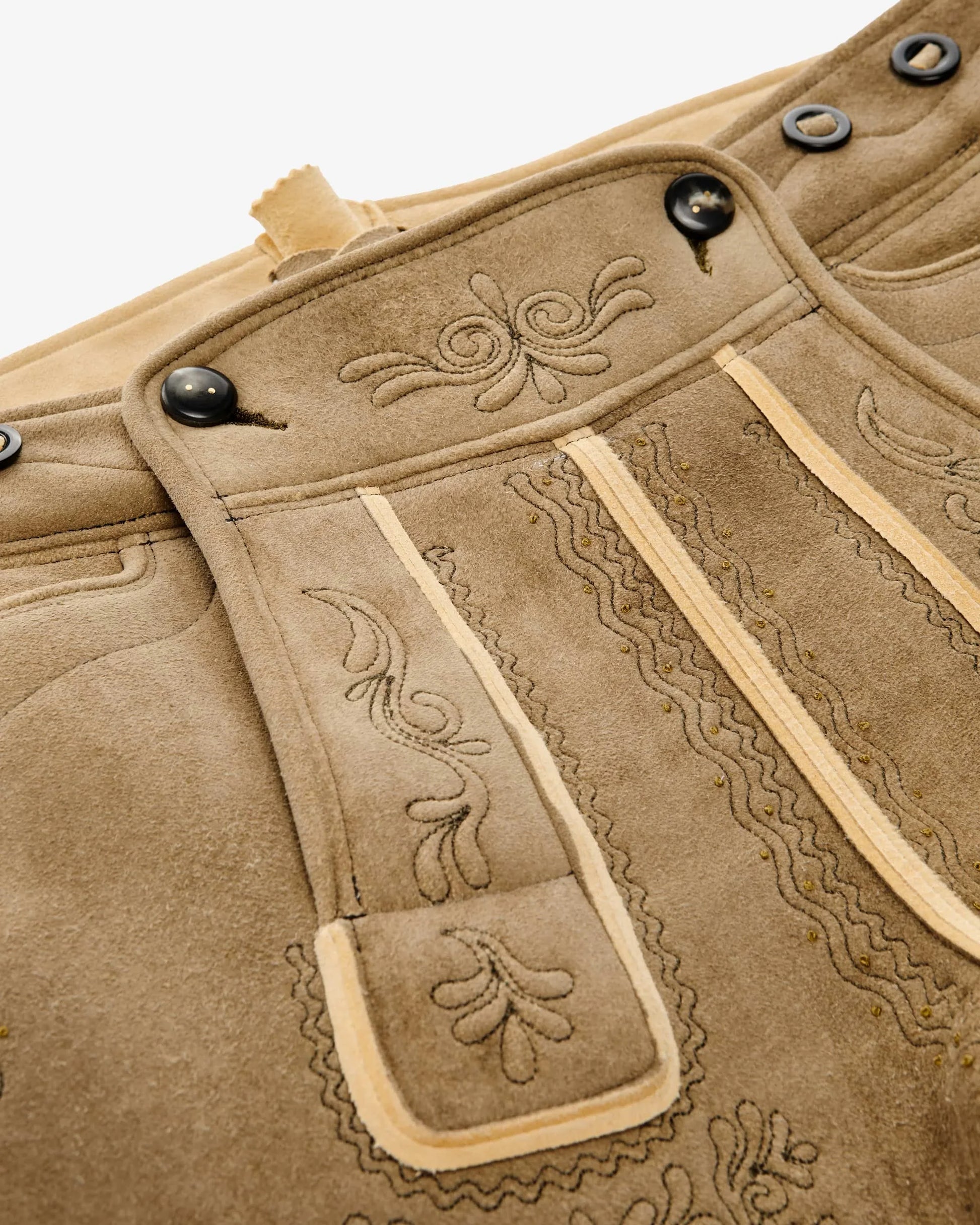Close-up of a brown leather jacket with intricate stitching and decorative patterns.