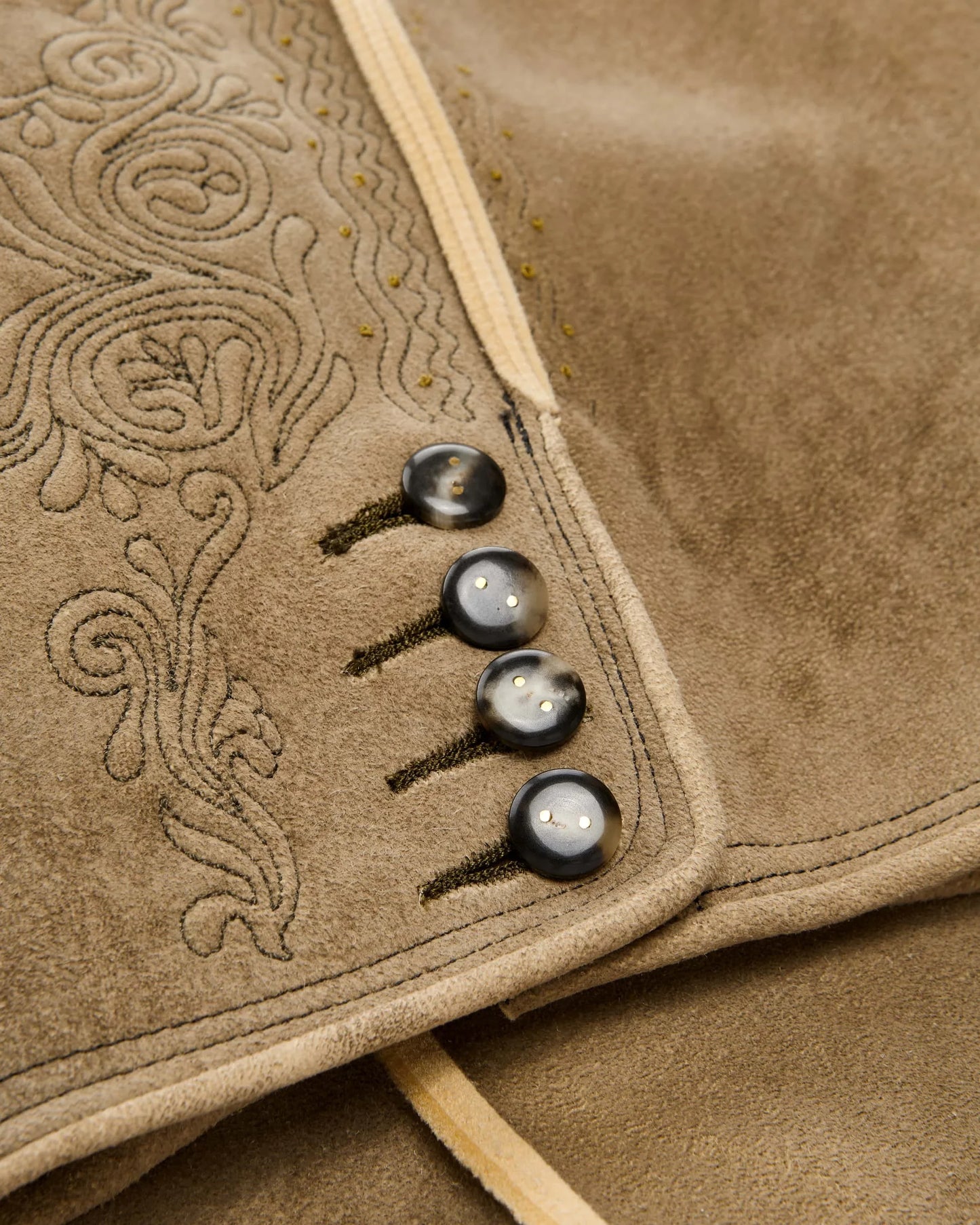 Close-up of a brown suede jacket with intricate stitching and buttons.