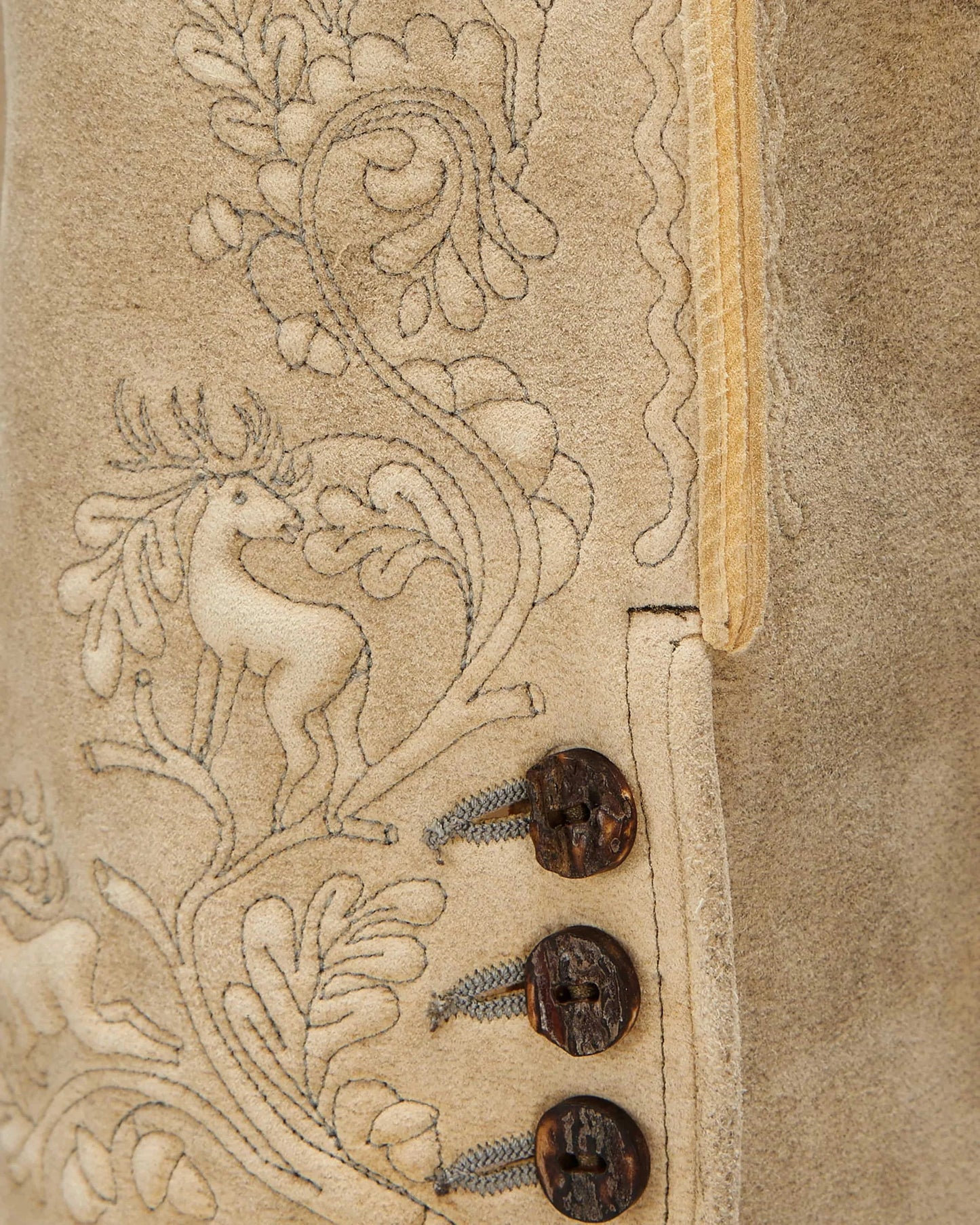 Close-up of a textured surface with intricate designs and buttons on a beige background