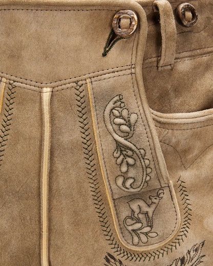 Close-up of brown leather pants with intricate stitching and embroidery.