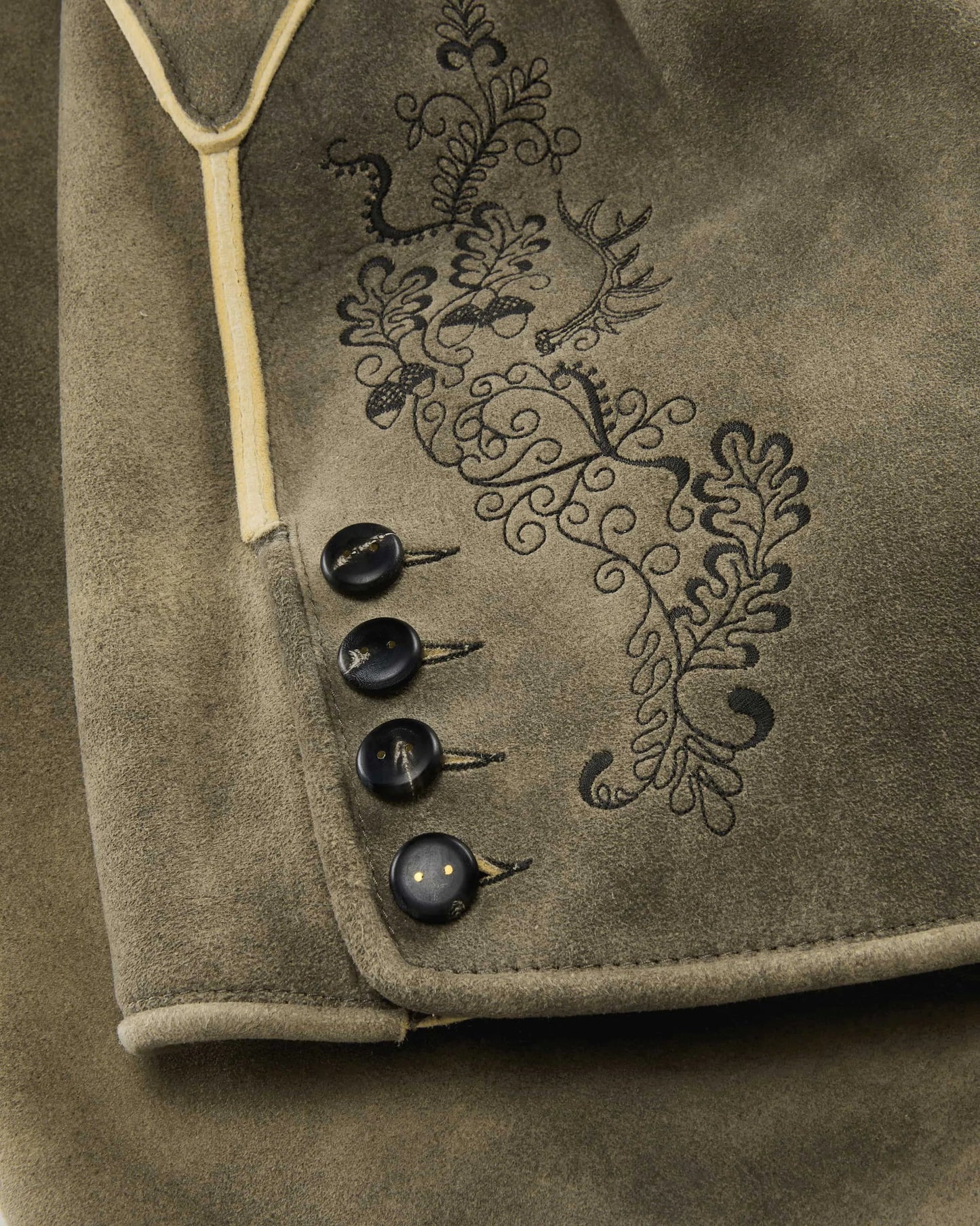Close-up of a brown fabric with embroidered design and buttons.