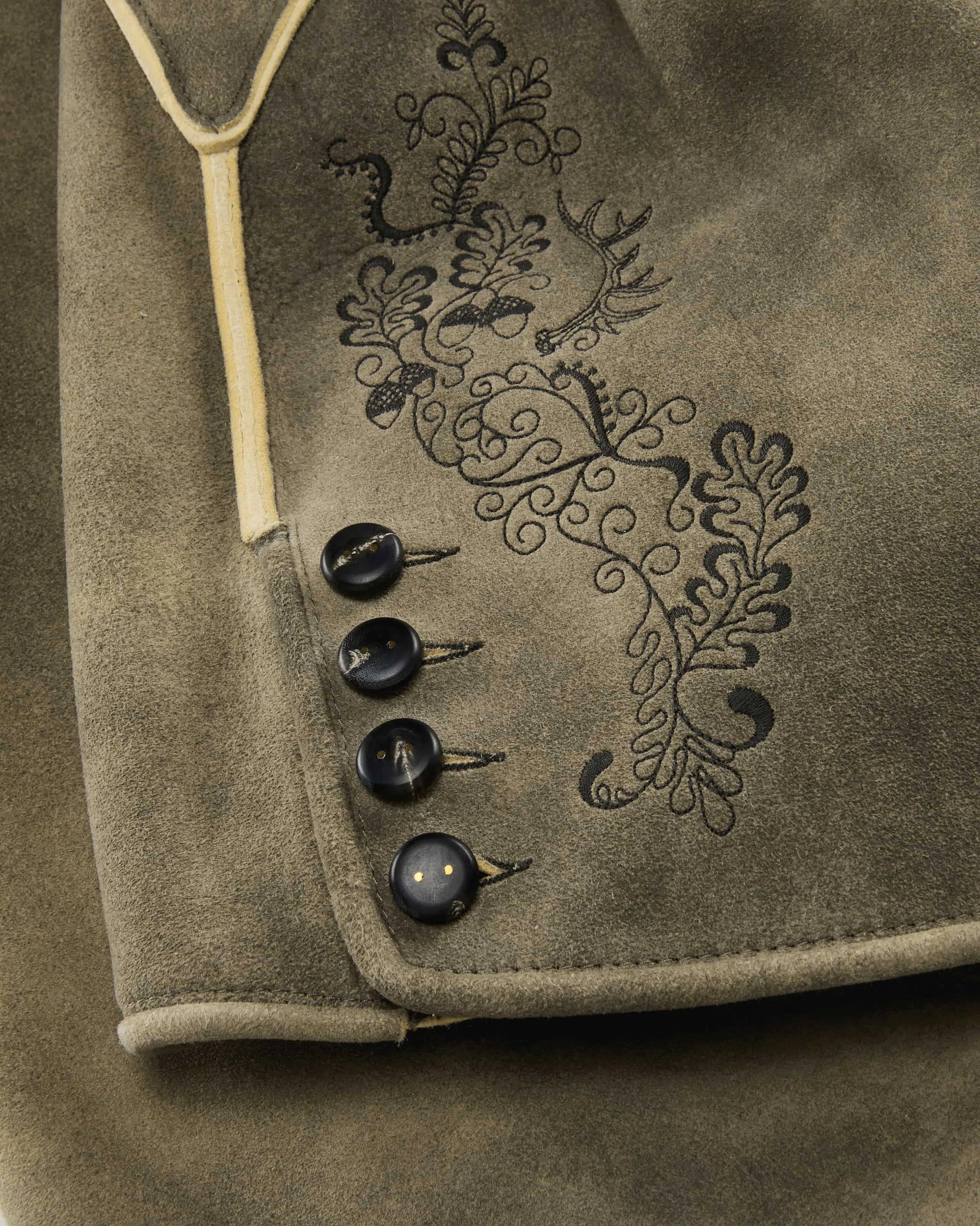 Close-up of a brown fabric with embroidered design and buttons.