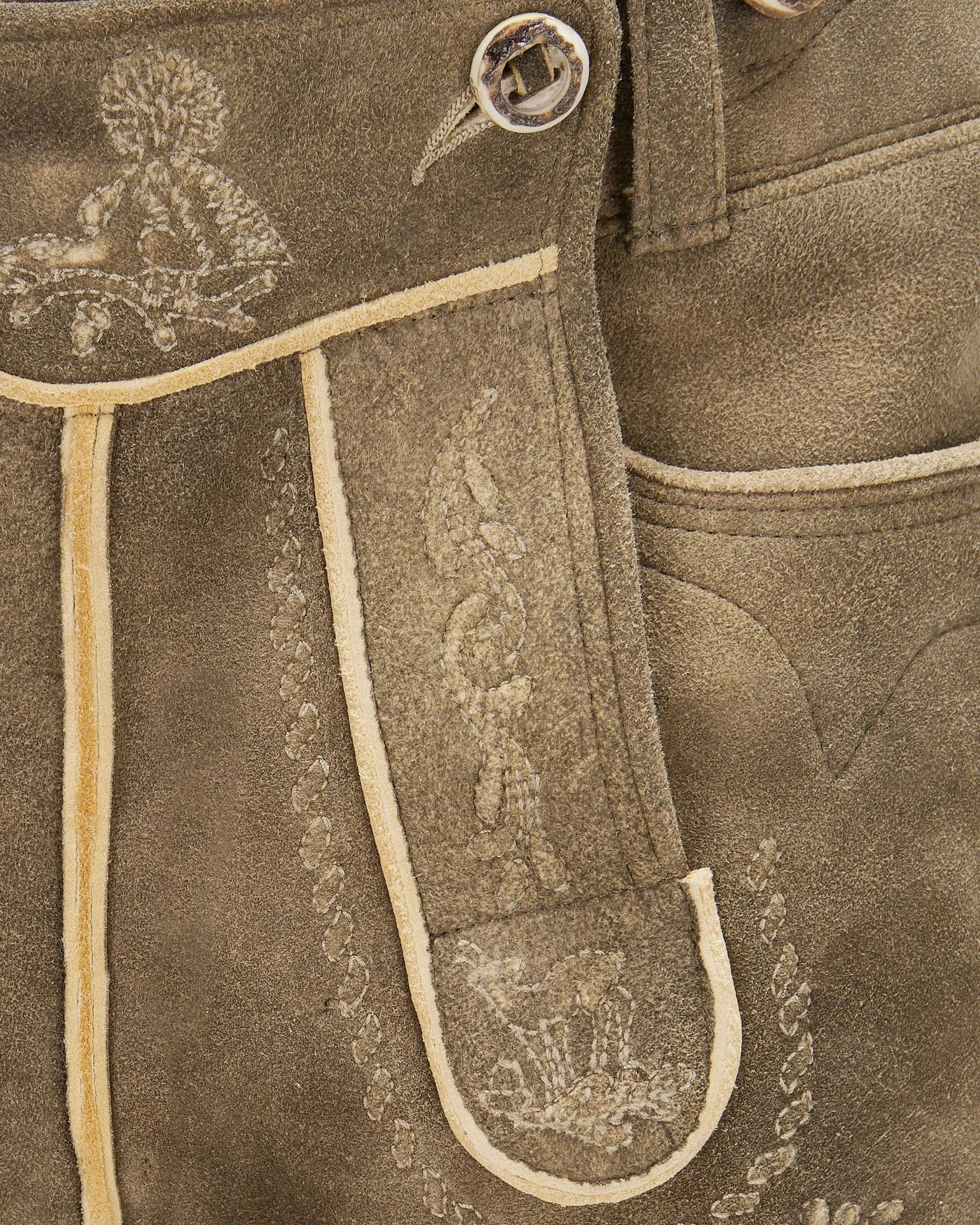 Close-up of brown leather pants with intricate white embroidery on a matching background