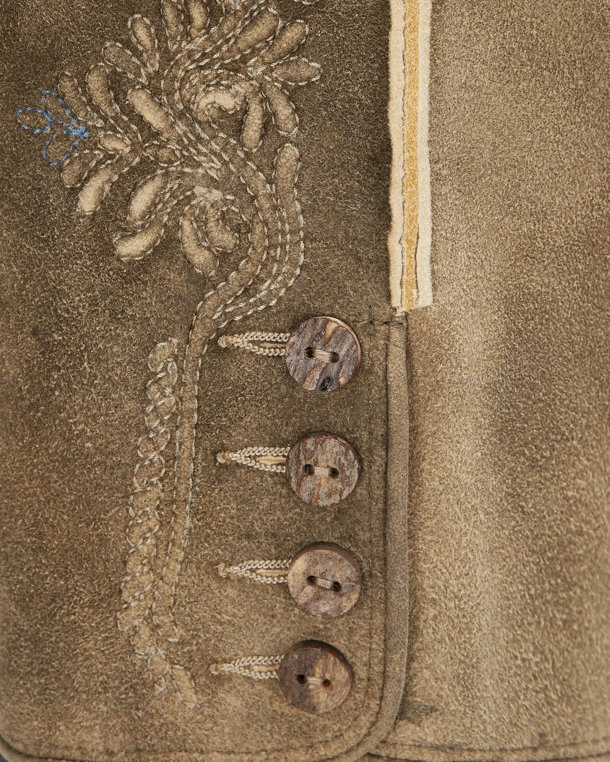 Close-up of a textured fabric with embroidered details and buttons.