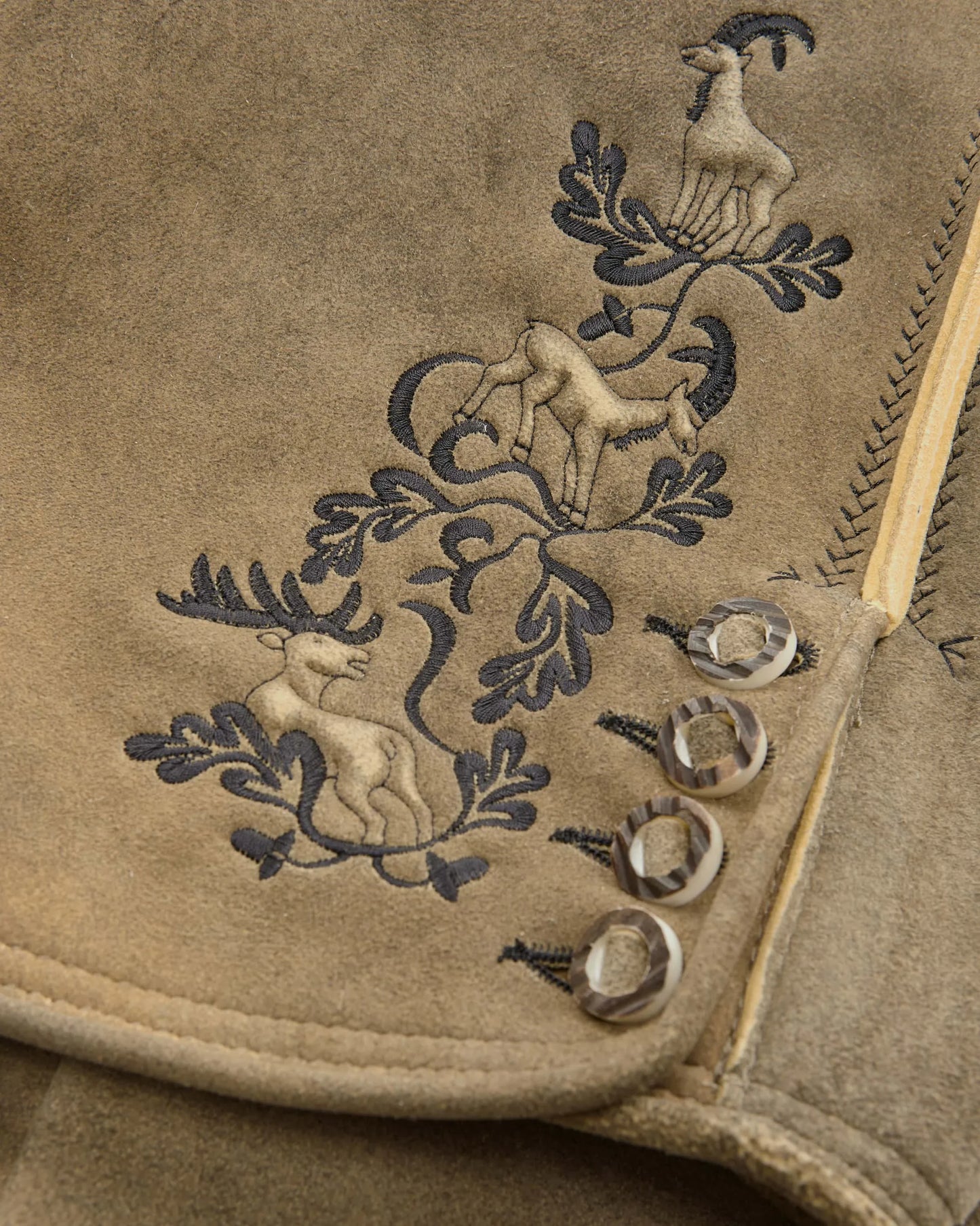 Embroidered design on a beige fabric with animals and leaves.