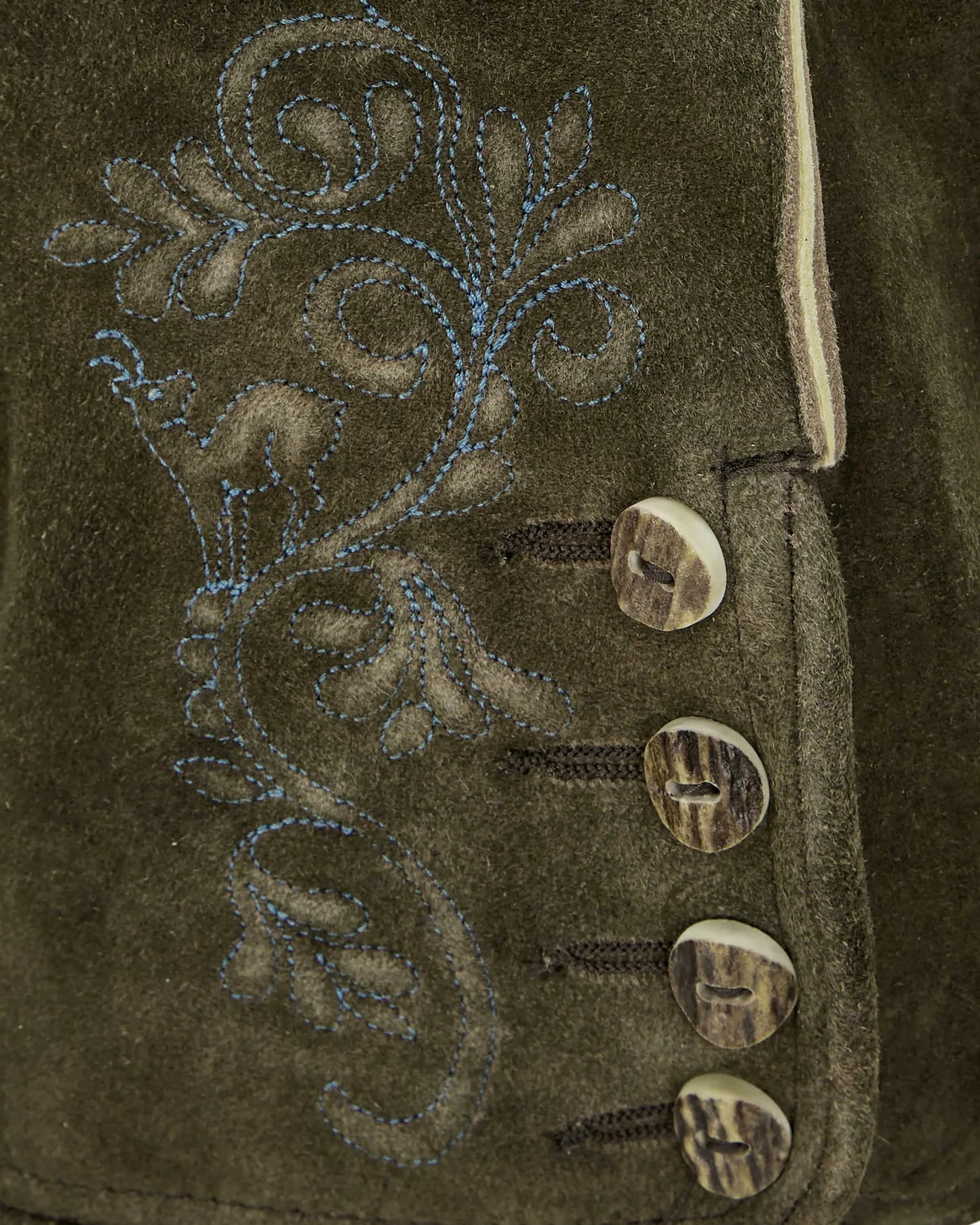 Close-up of a brown suede jacket with intricate floral embroidery and decorative buttons.