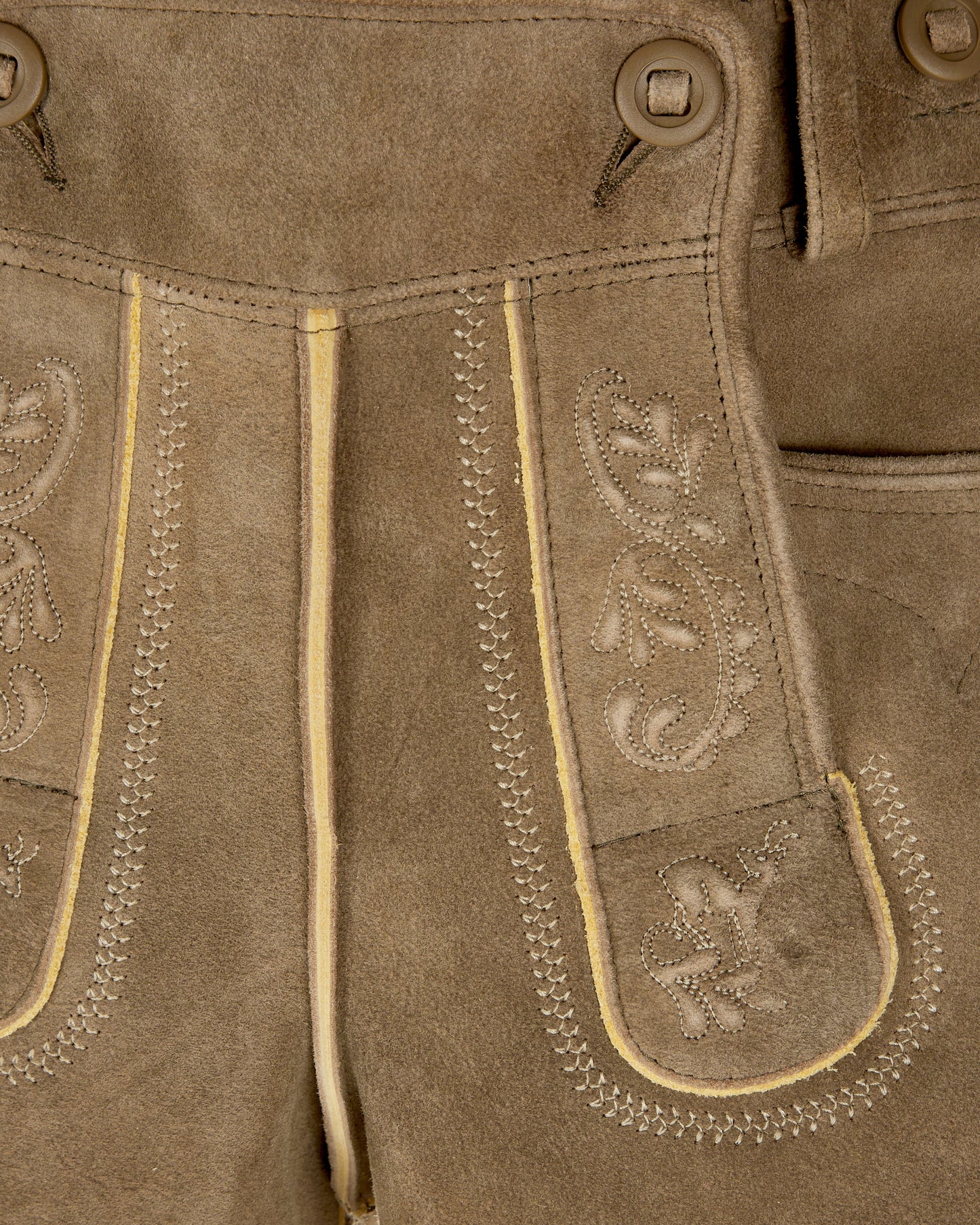 Close-up of brown leather pants with decorative stitching and patterns.