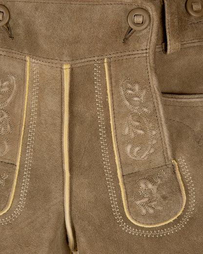 Close-up of brown leather pants with decorative stitching and patterns.