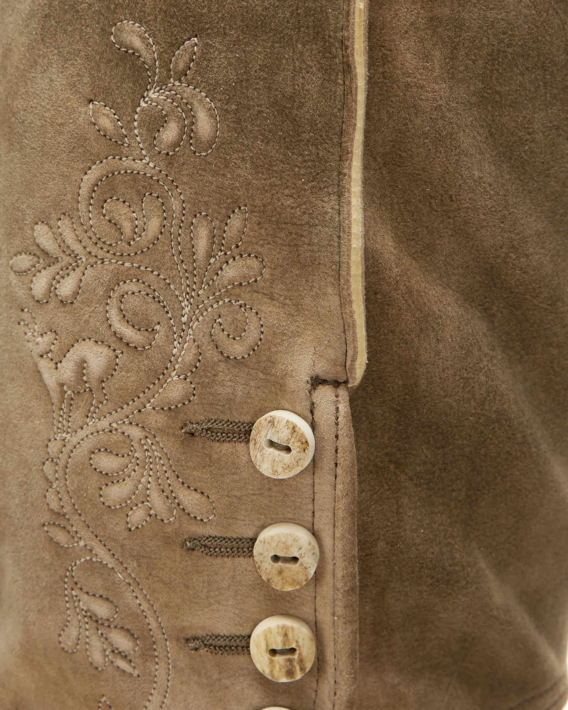 Close-up of a brown suede jacket with intricate embroidery and buttons.