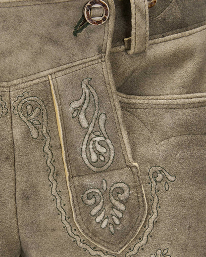 Close-up of a brown leather apron with intricate white embroidery on a matching background.