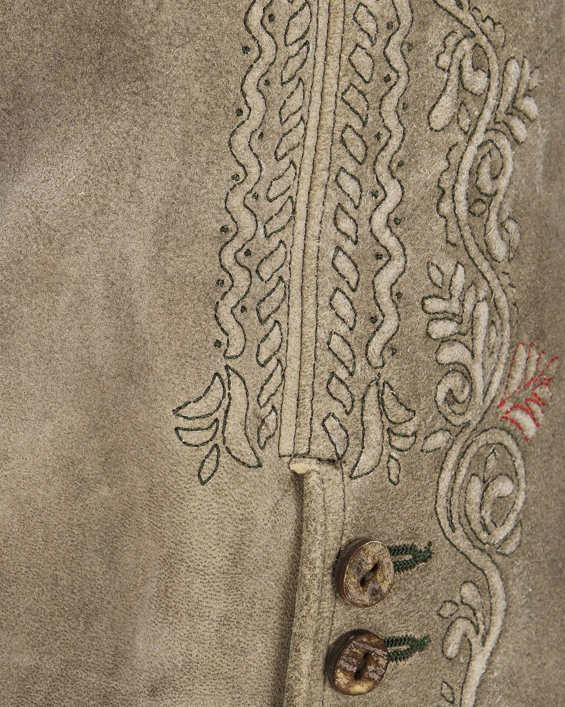 Close-up of embroidered fabric with intricate patterns on a beige background