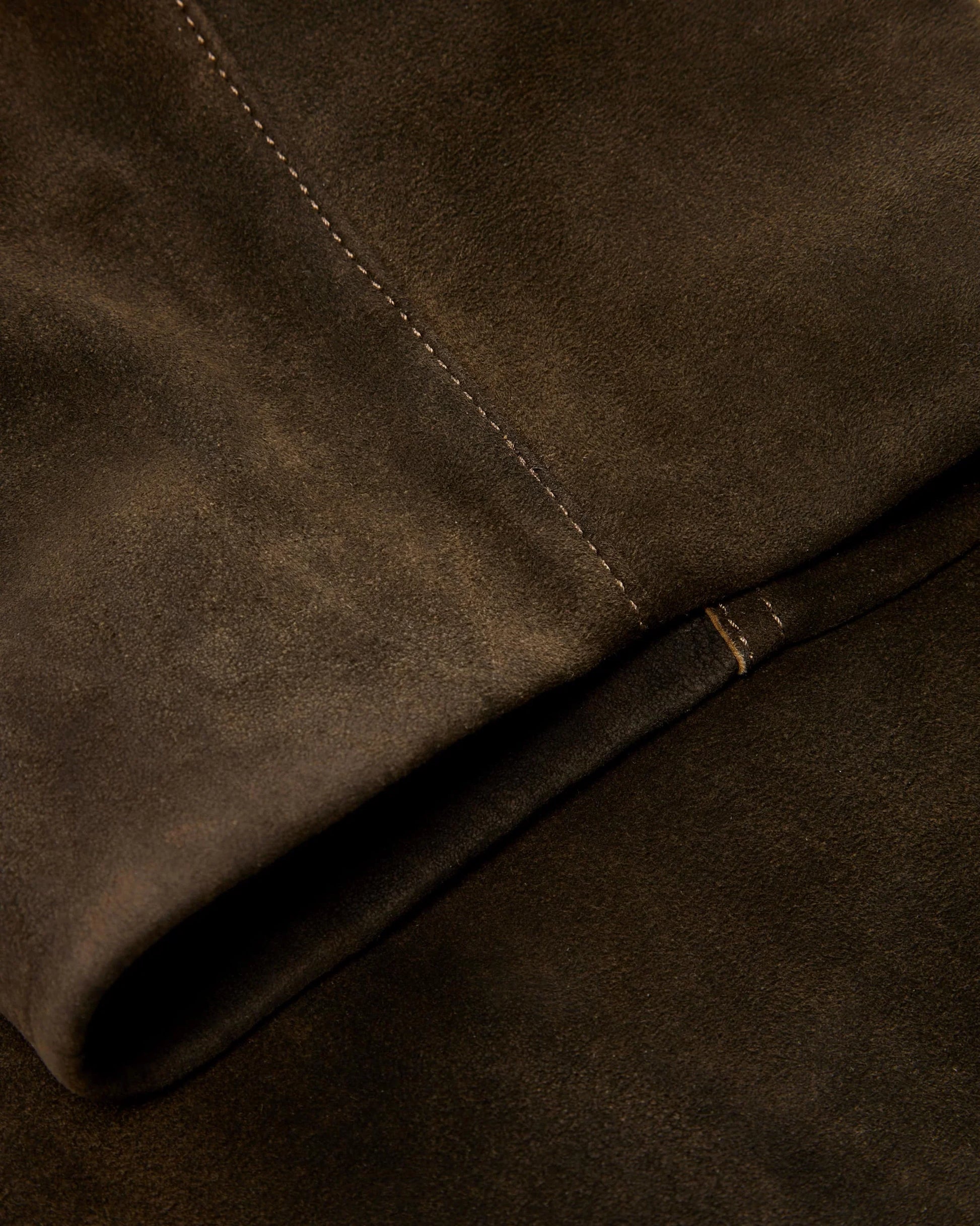 Close-up of brown suede fabric with a visible seam.