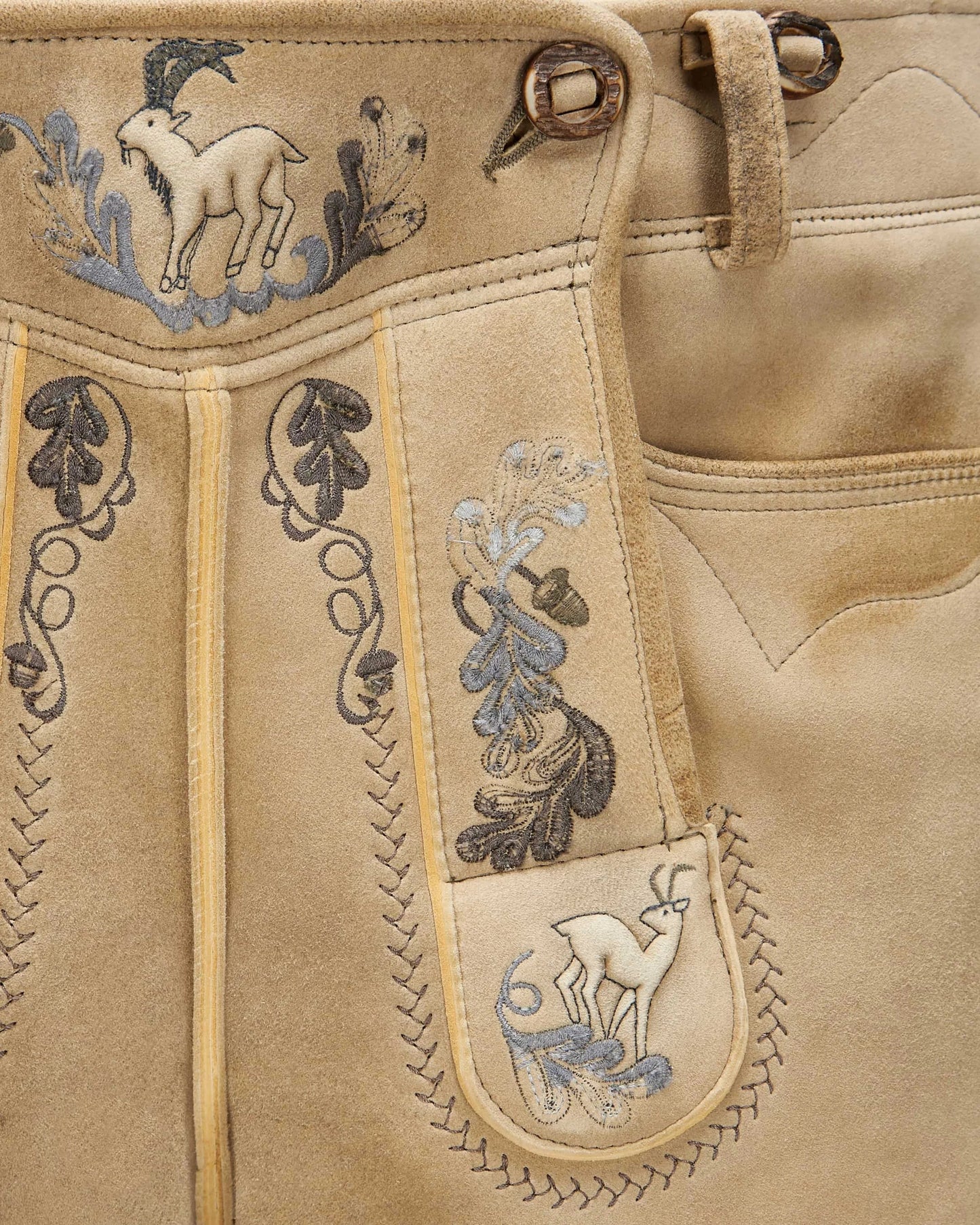 Beige leather outfit with intricate embroidery featuring animals and floral patterns.