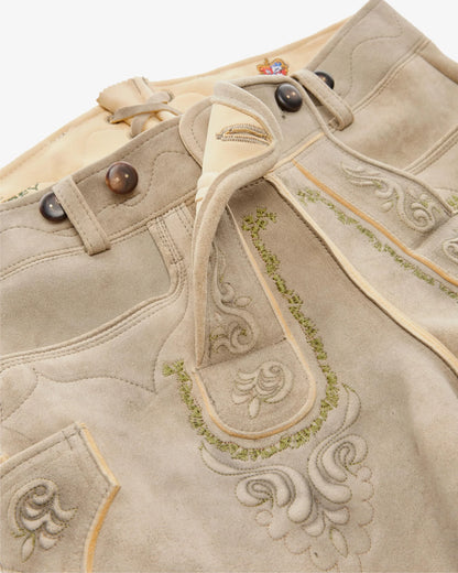 Close-up of a beige fabric with intricate embroidery and decorative buttons.