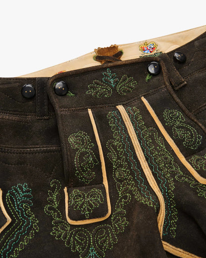 Close-up of a traditional black leather outfit with green embroidery on a white background