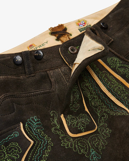 Close-up of a black leather jacket with green embroidery and buttons, featuring a brand logo on a white background.