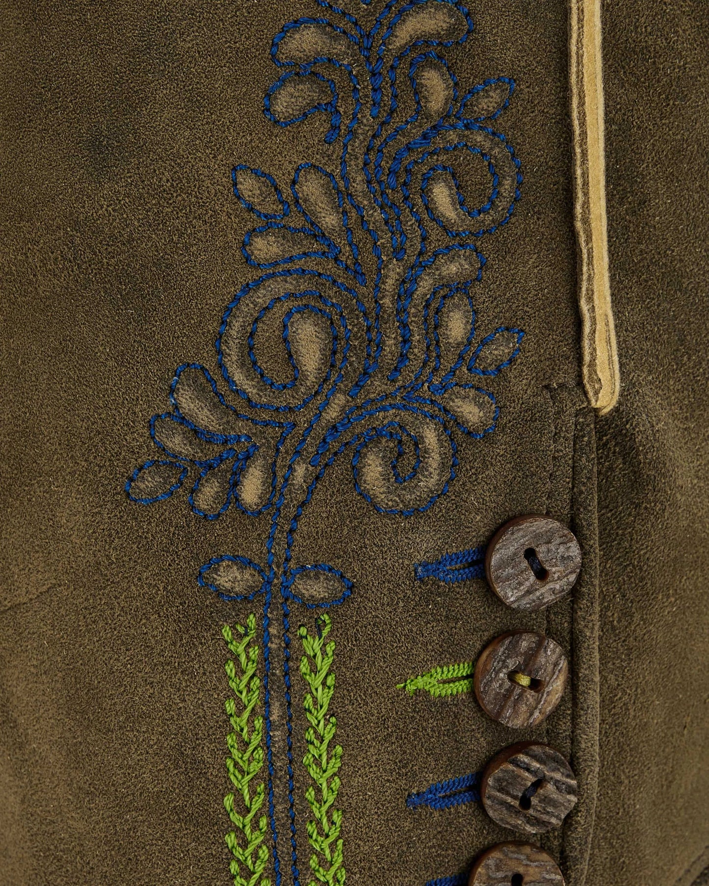Close-up of a brown fabric with embroidered floral design and wooden buttons.