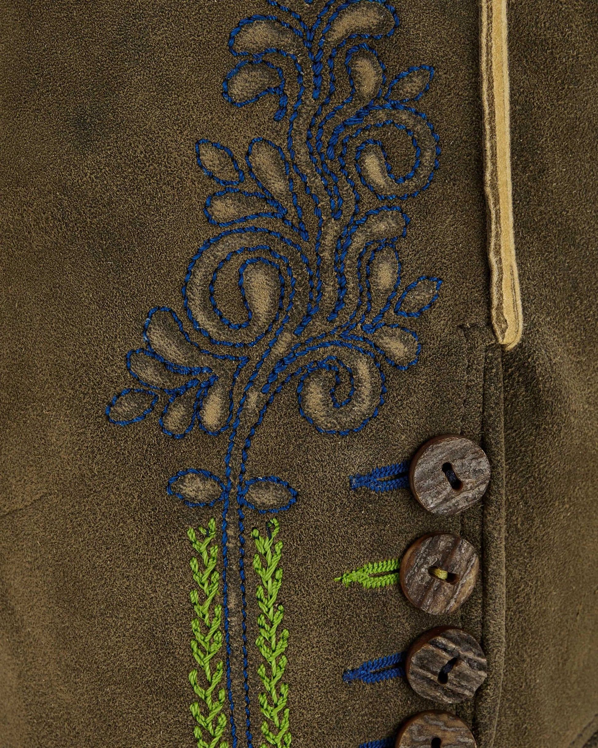 Close-up of a brown fabric with embroidered floral design and wooden buttons.