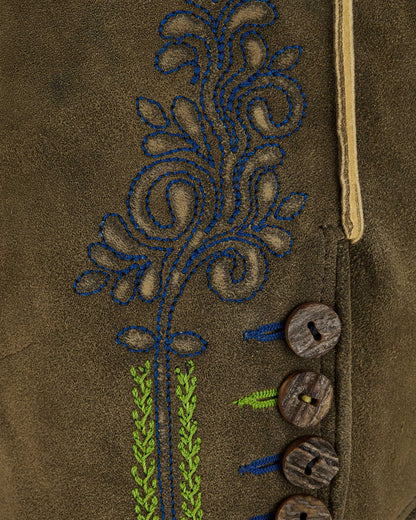 Close-up of a brown fabric with embroidered floral design and wooden buttons.