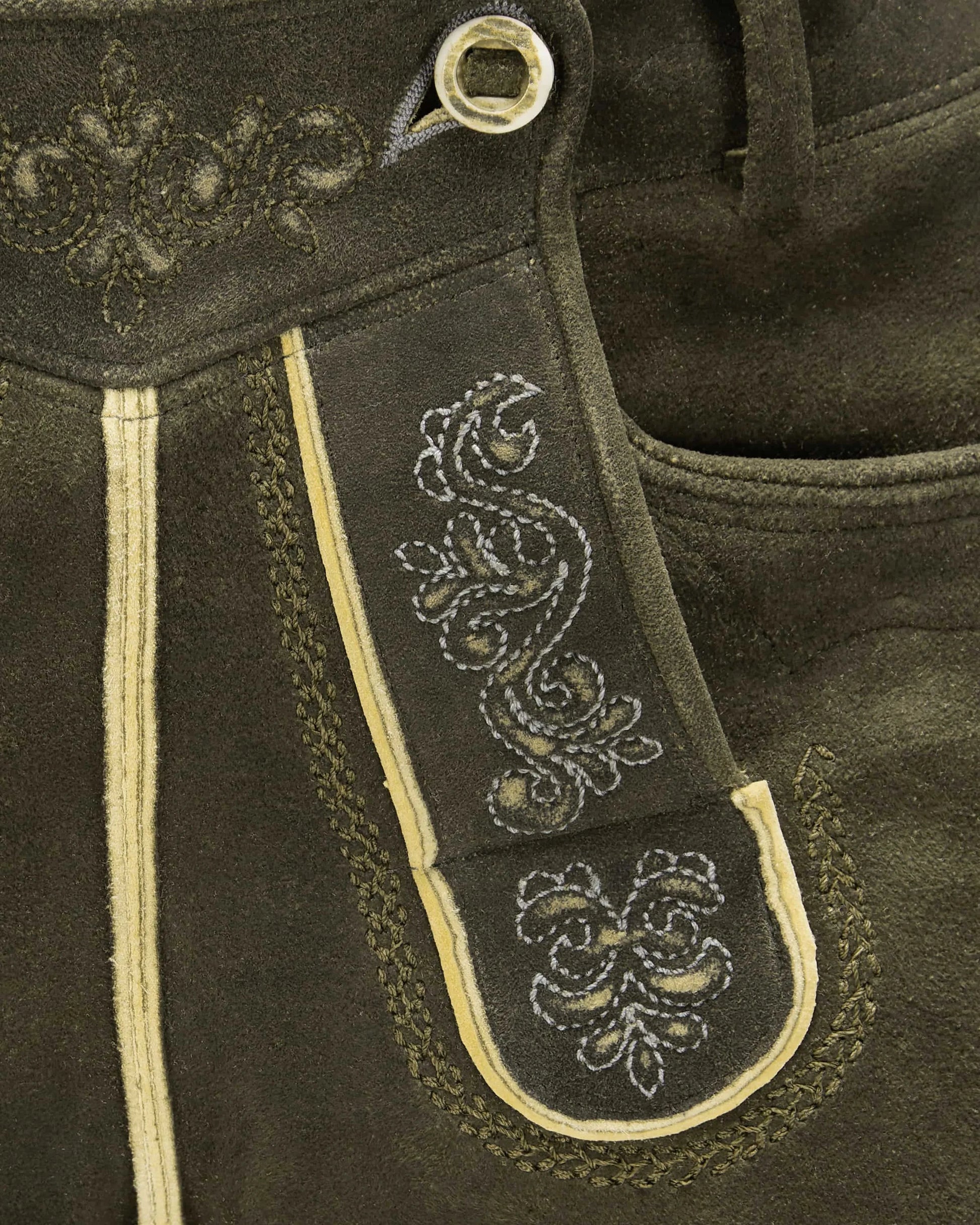 Close-up of dark brown leather with intricate white embroidery on a strap.