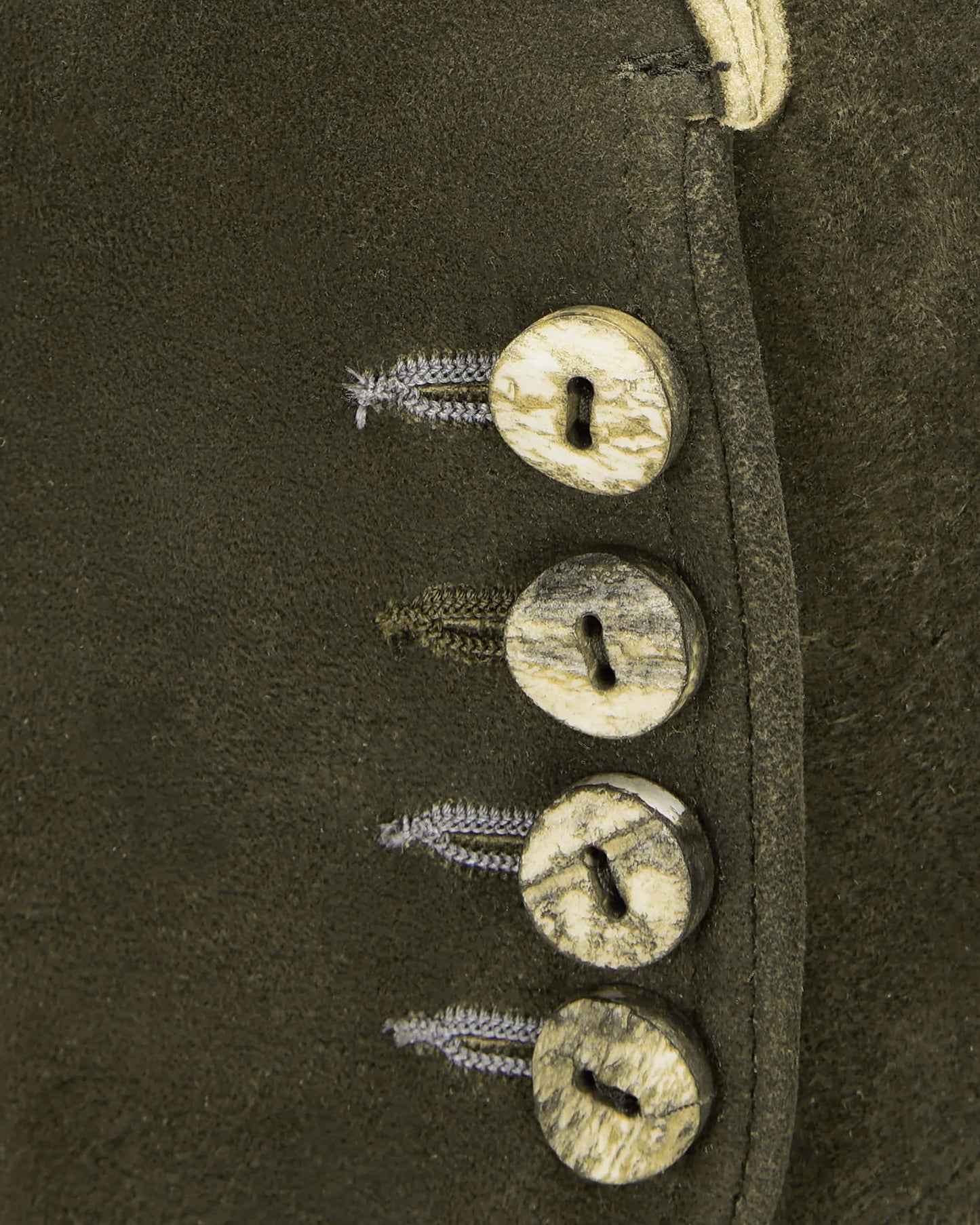 Close-up of a leather boot with metal buttons and laces on a dark background
