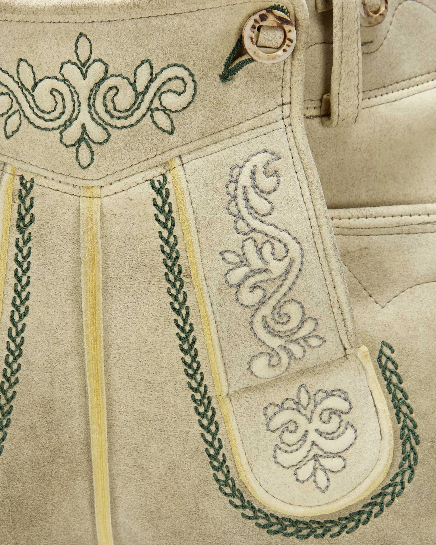 Close-up of beige traditional embroidered pants with green and white patterns.