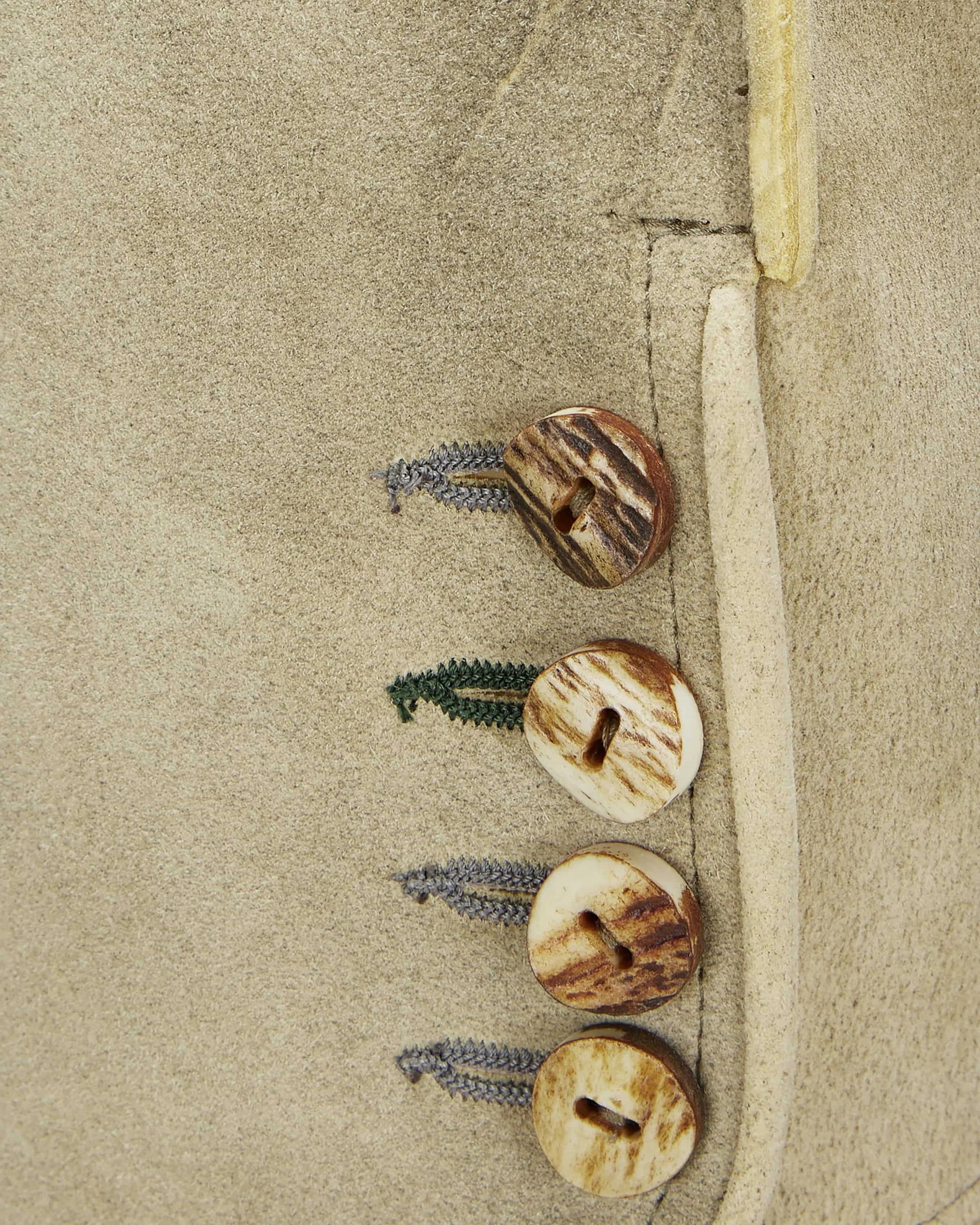 Three wooden buttons with leaves on a beige fabric background