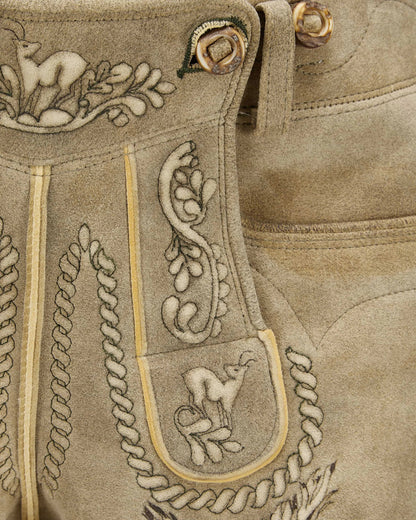 Close-up of a brown leather boot with intricate embroidery and decorative elements.